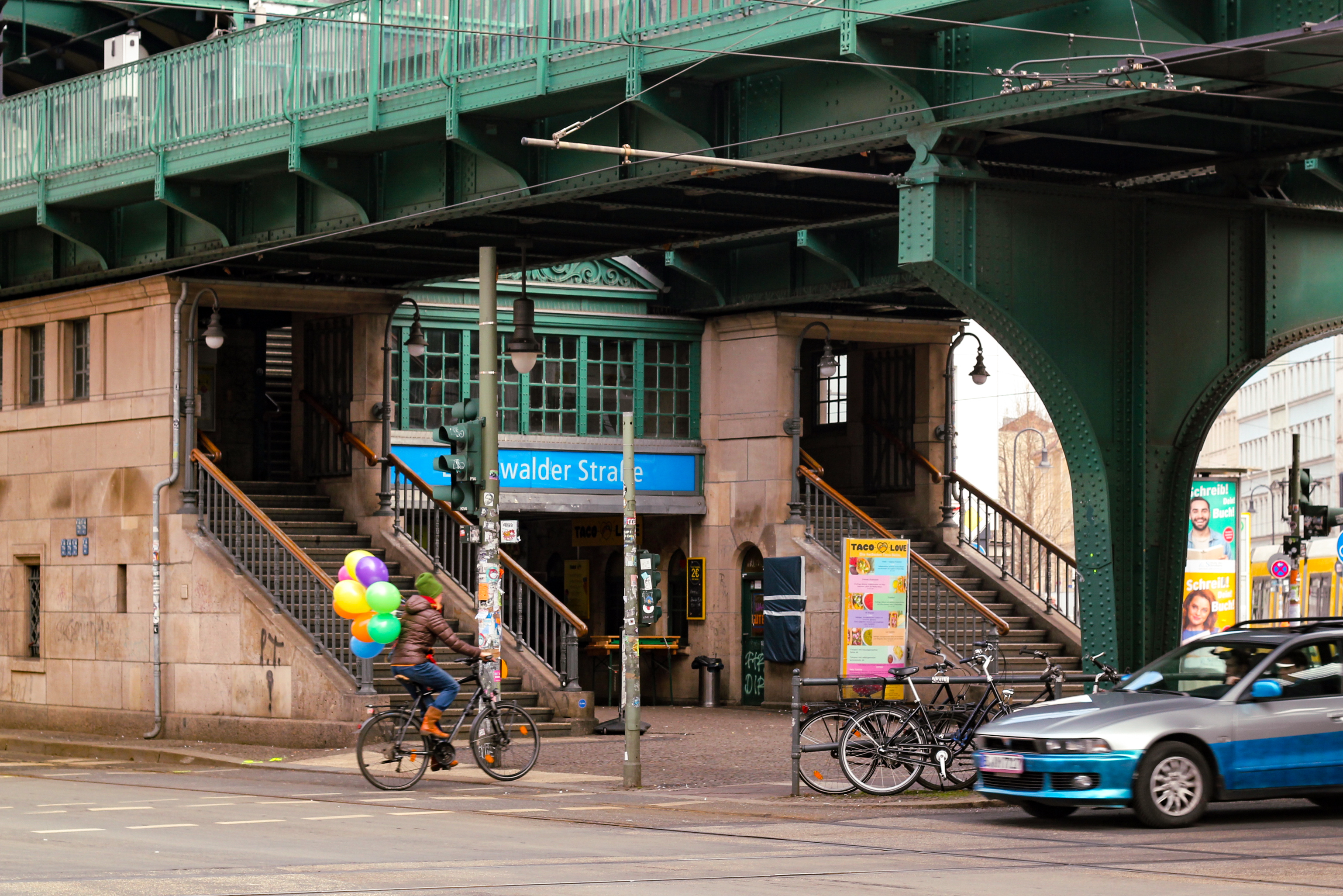 Le pont de la station de métro Eberswalder strasse avec un cycliste transportant des ballons colorés