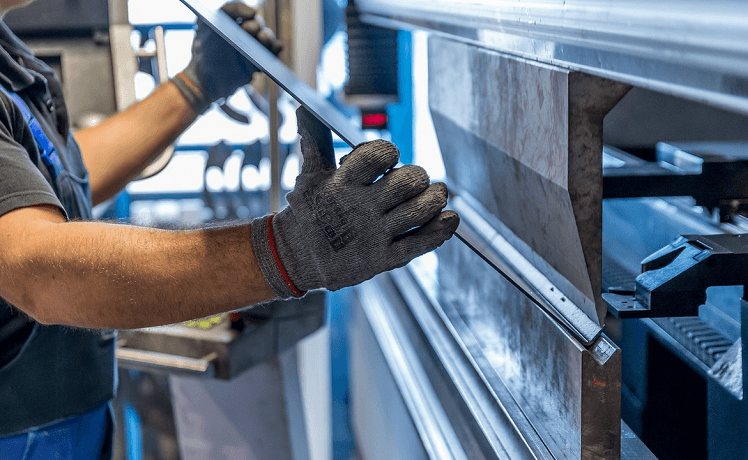 un homme avec des gants travaille l'acier industriel