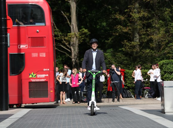 Un homme en trottinette dans une rue londonienne 