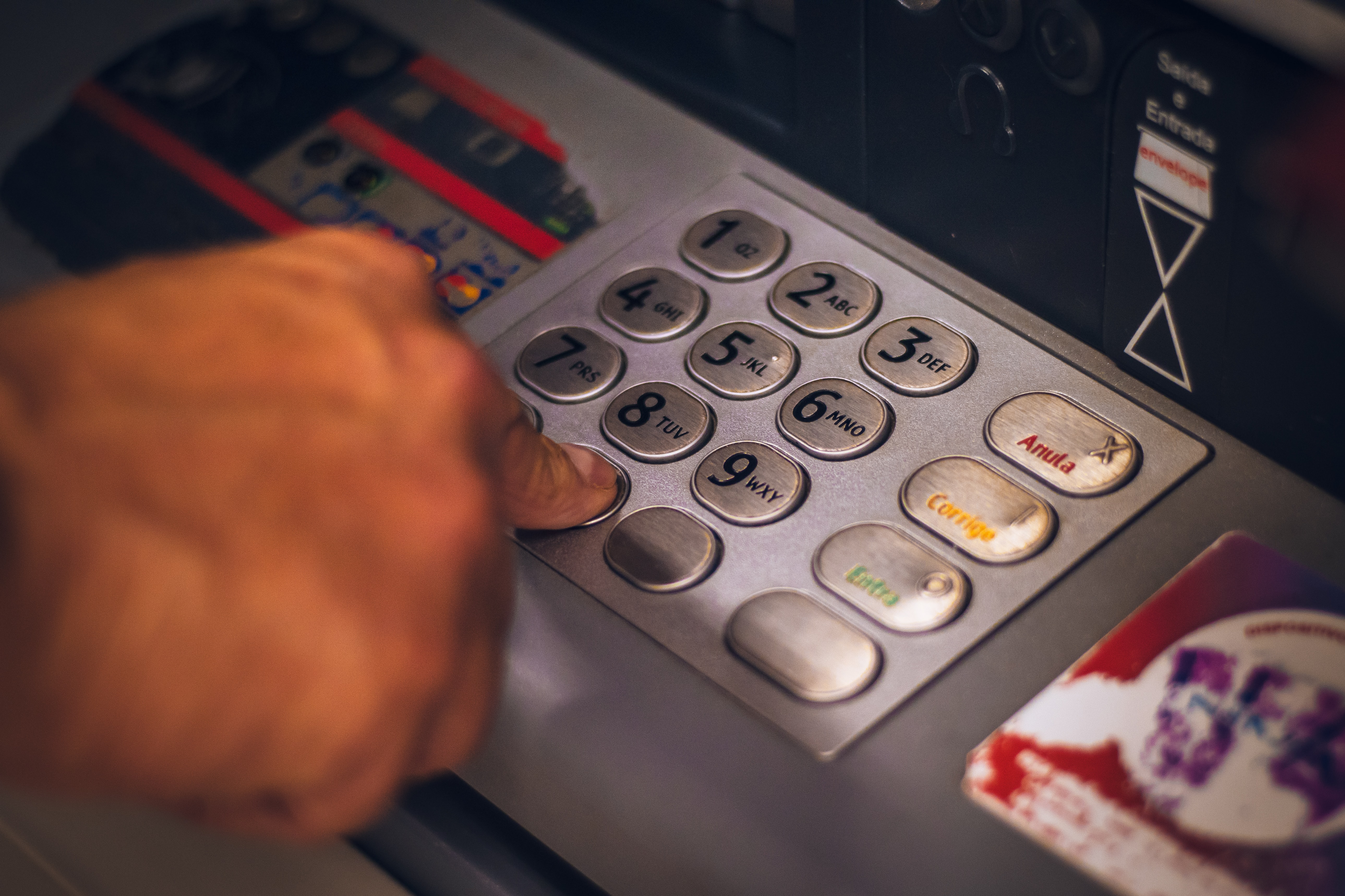 personne qui tape son code sur automate pour retirer de l'argent