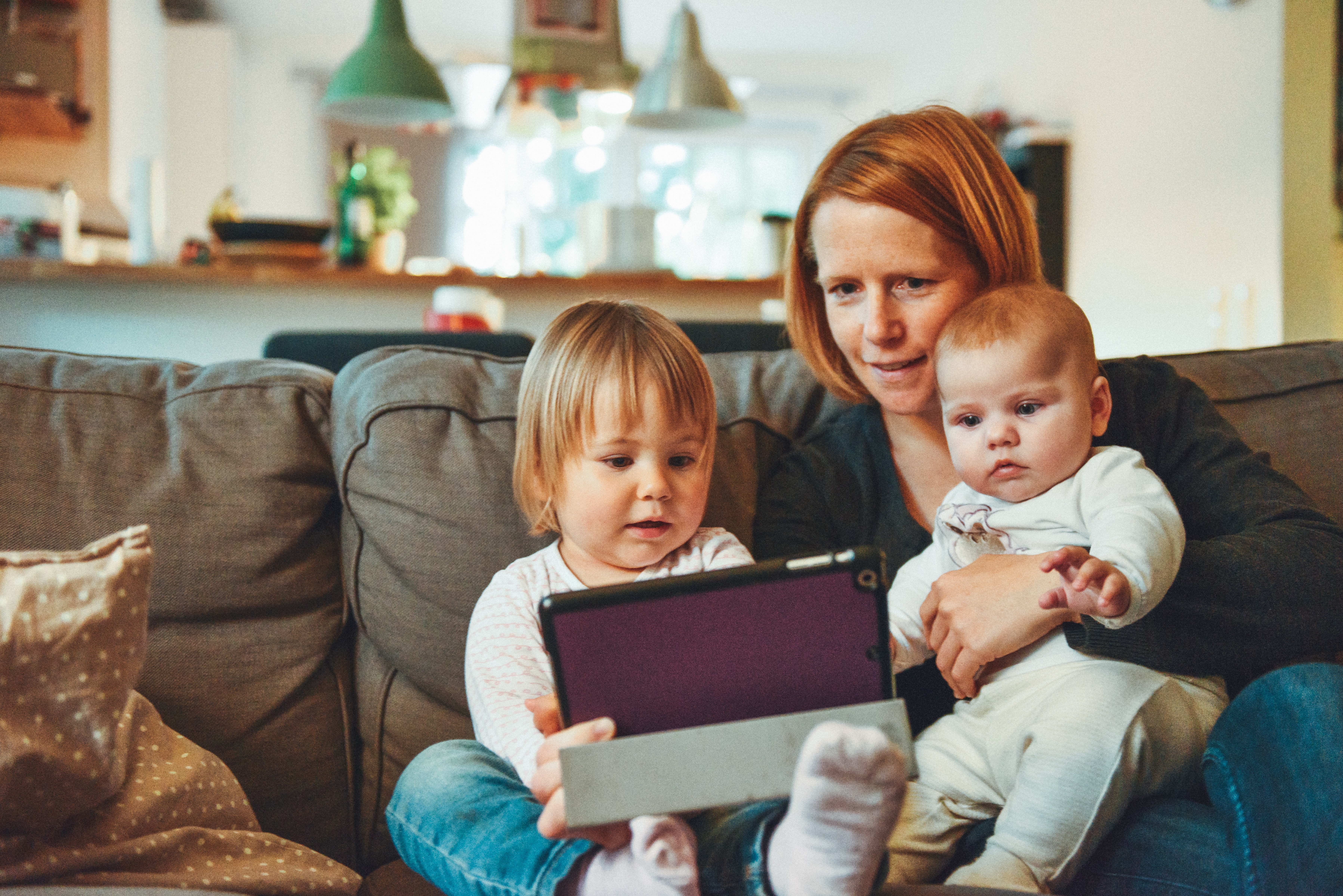 femme avec ses enfants entrain de regarder une tablette electronique