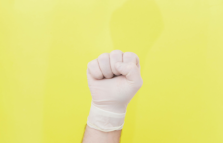 le poing levé avec un gant chirurgical sur fond jaune