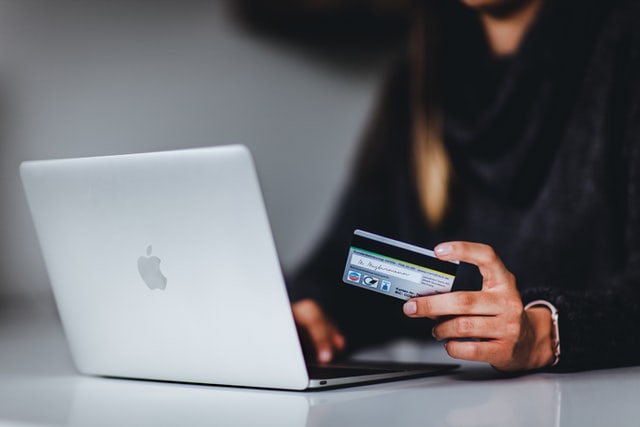 femme qui fait du shopping en ligne avec sa CB et son Mac