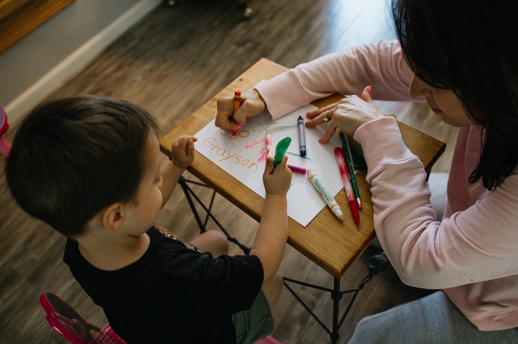 Dans une nursery, une professionnelle de l'enfance dessine avec un enfant