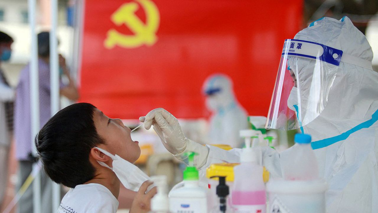 une personne en blouse test un enfant pour le covid en Chine