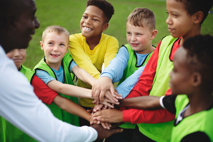 junior-football-team-stacking-hands-before-match