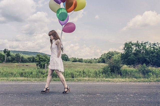 femme qui marche sur la route avec des ballons 