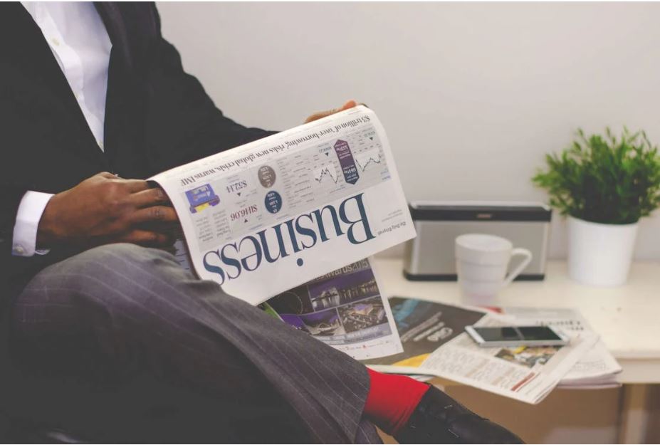 Homme en costume assis  en lisant un journal "Business"