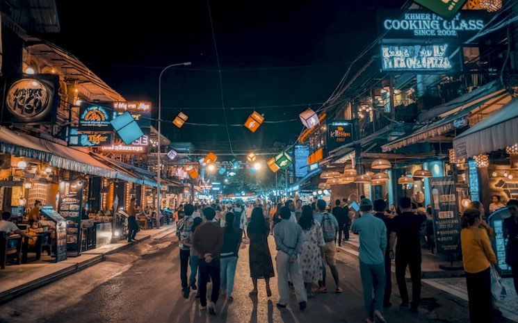une rue éclairée et animée le soir au Cambodge