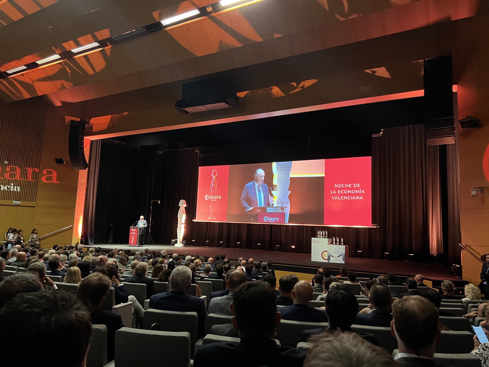 une personne en train de parler au public dans un théâtre lors de la noche de la economia