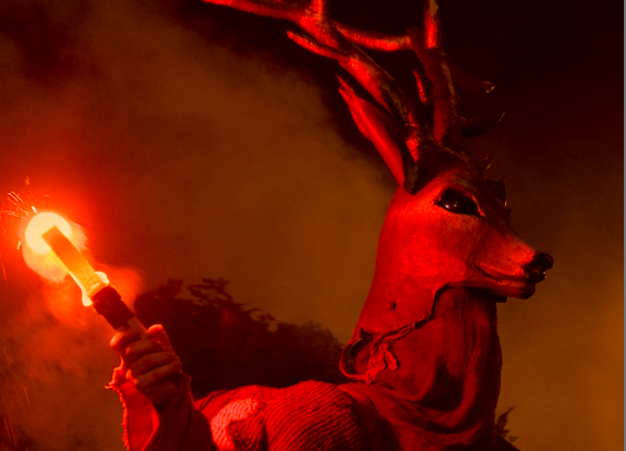 quelqu'un déguisé en cerf avec un flambeau