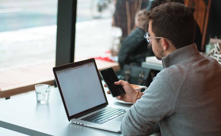 Un jeune homme travaille sur son PC et smartphone - joseph-frank-unsplash