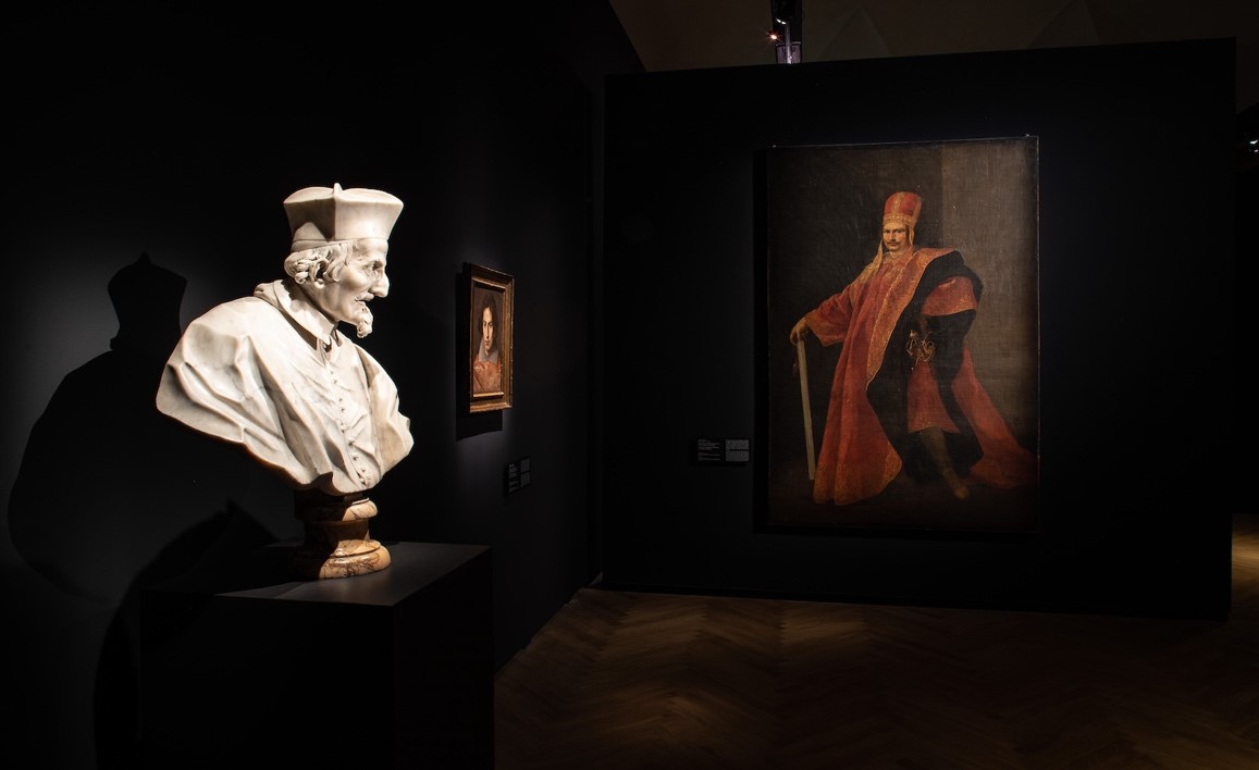 une sculpture d'un buste et un tableau exposés dans la pénombre d'un musée à Rome