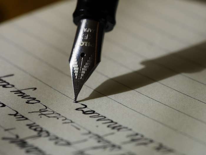 une stylo plume en train d'écrire un texte sur un papier