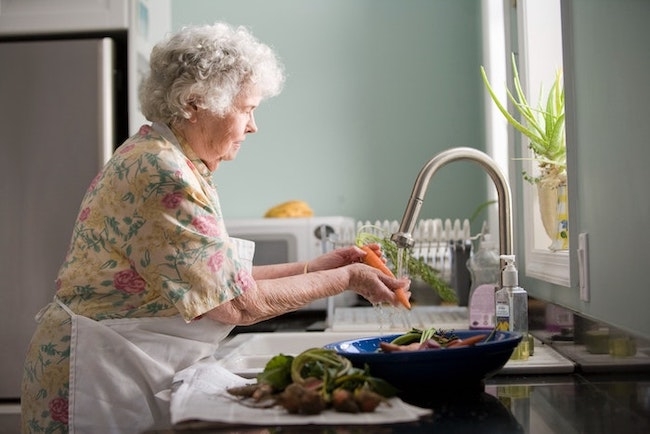 Une domestique âgée nettoie la cuisine
