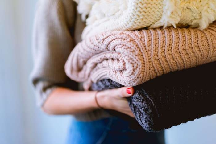 une personne avec des pulls en laine dans ses mains